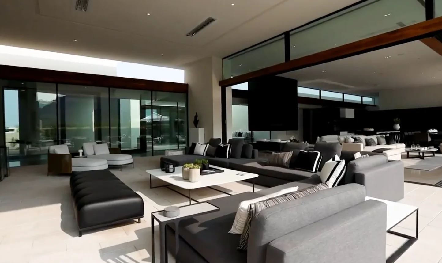 Covered seating area with grey sofas under a timber-lined roof