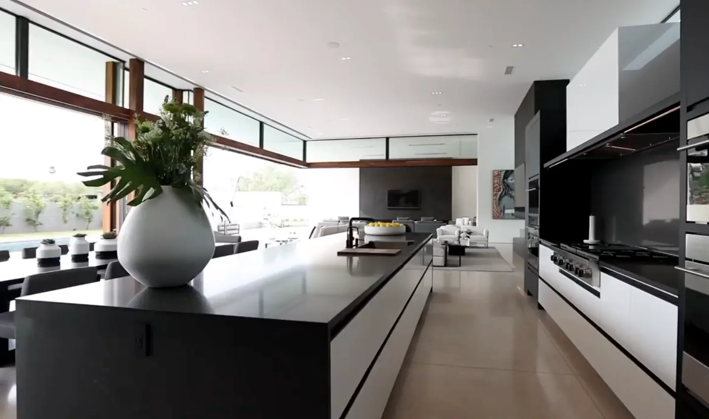 Black kitchen with a long island and a white vase